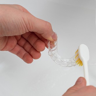 Patient cleaning clear aligner in sink