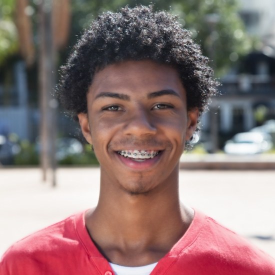 Young man smiling outdoors with advanced Damon braces in Wayland