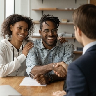 Man shaking hands with man sitting across desk