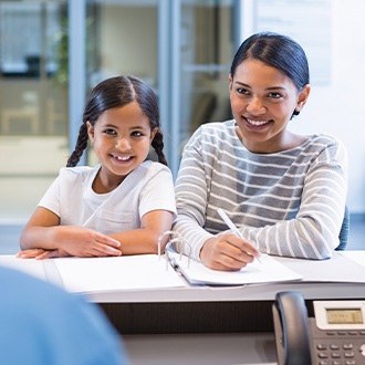 Mother and young daughter looking at orthodontic team member at front desk