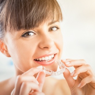 Smiling woman holding Invisalign tray