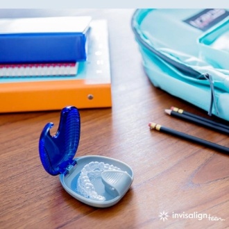 Invisalign aligners in their case on a desk with school supplies
