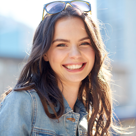 Woman smiling outdoors after seeing orthodontist in Wayland