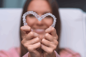 a patient smiling and holding their Invisalign aligners